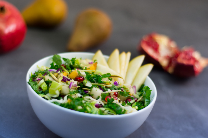 A mixed green and kale salad mixed with pomegranate and pears